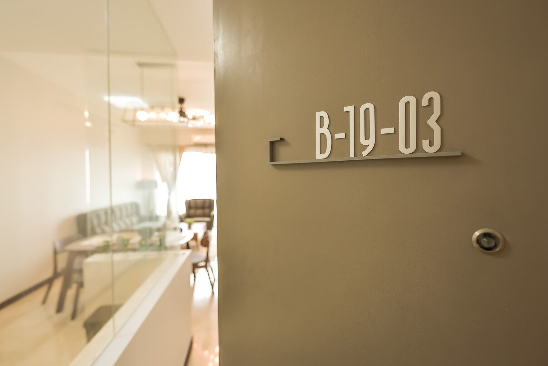 A door with a room number B-19-03 on a beige wall.