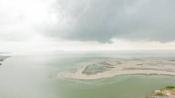 An aerial view of a coastal area with a large body of water, a sandy beach, and a stormy sky.