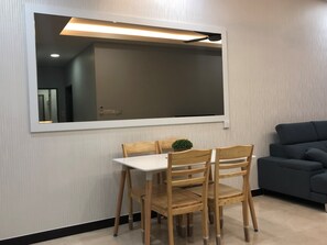 Un comedor con una mesa y sillas, un espejo grande y un sofá de color oscuro.