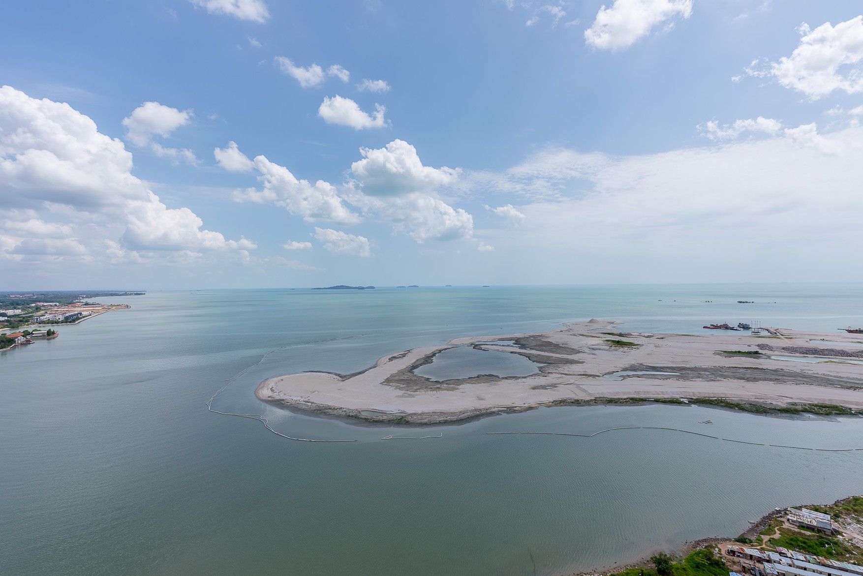 A coastal landscape with a sandy beach, calm waters, and a clear sky.