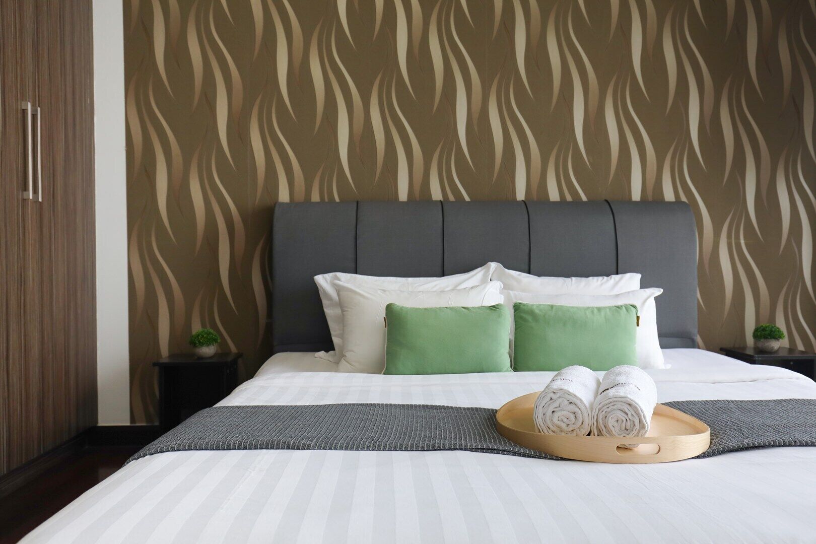 Een hotelkamer met een groot bed, een grijze hoofdbord en behang met een patroon.