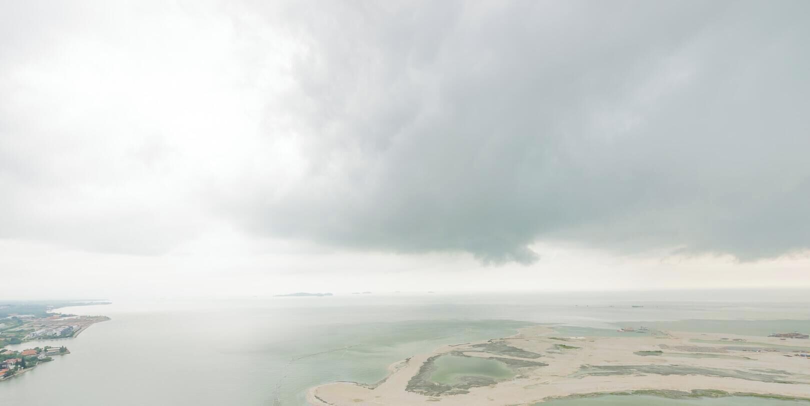 Vista aérea de una zona costera con una extensión de agua, una playa arenosa y una pequeña isla.