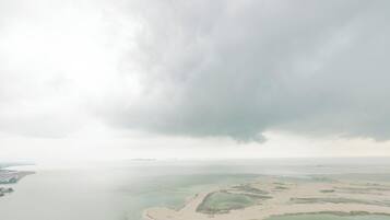 Vista aérea de una zona costera con una extensión de agua, una playa arenosa y una pequeña isla.
