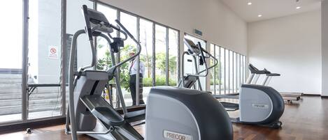A gym with two Precor USA elliptical machines, a mirrored wall, and a large window with a view of the outside.