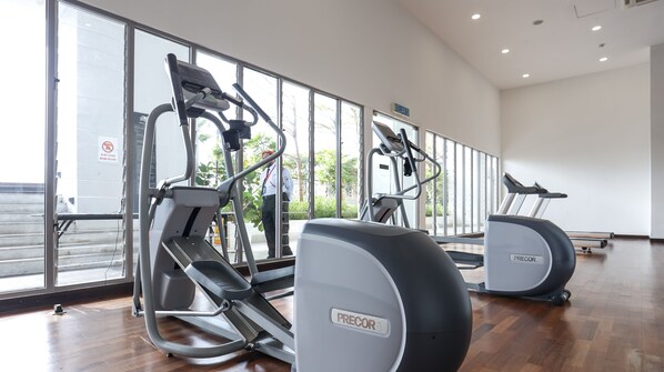 Un gimnasio con dos máquinas elípticas Precor USA, un espejo grande y un ventanal con vistas al exterior.