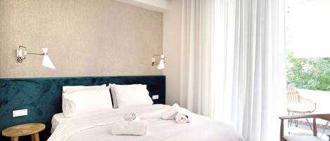 A neatly made bed with white linens, a teal upholstered headboard, and two wall-mounted lamps.