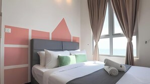 Un hotel moderno con cama, almohadas y vistas al mar a través de amplios ventanales.