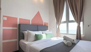 Un hotel moderno con cama, almohadas y vistas al mar a través de amplios ventanales.