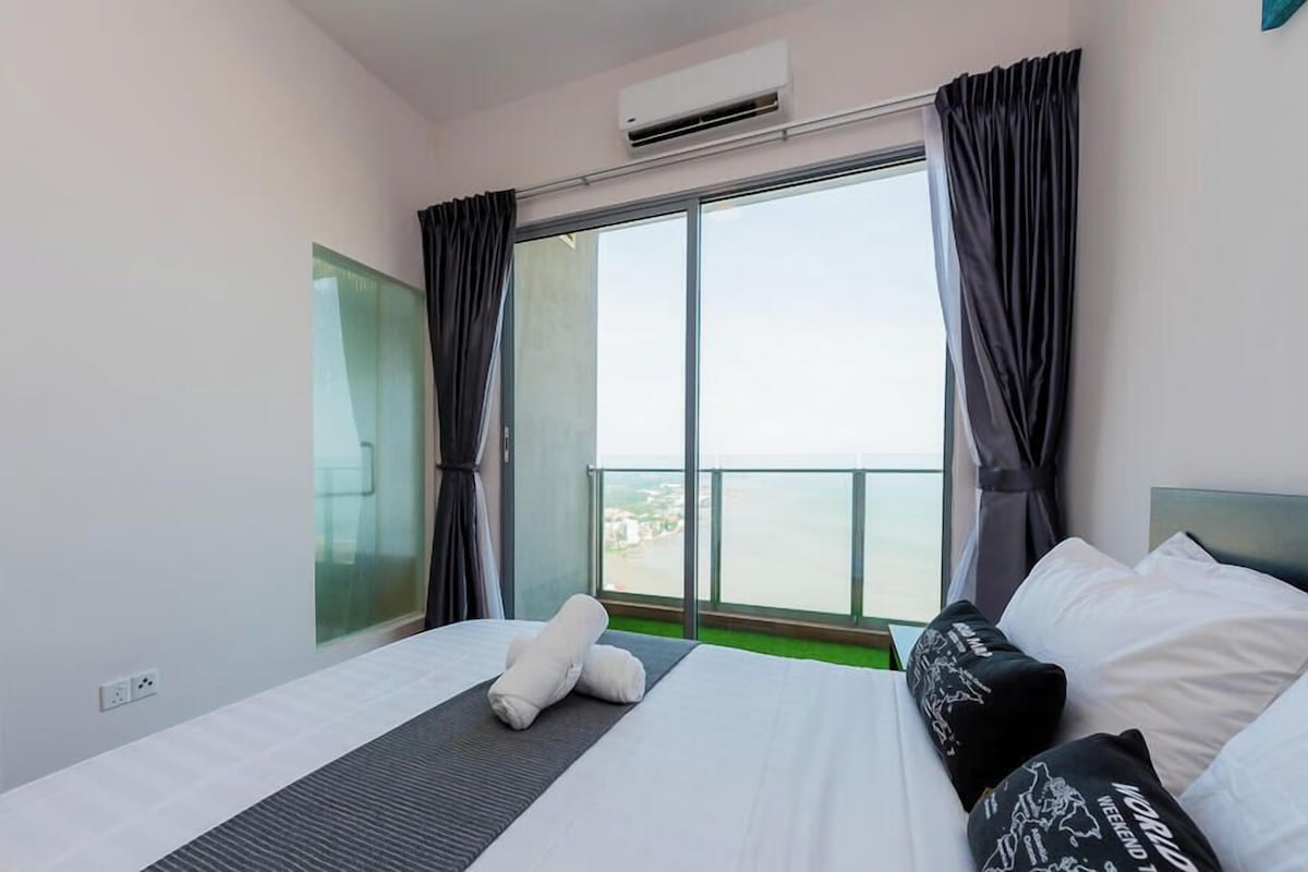 A hotel room with a bed, a window with curtains, an air conditioning unit, and a view of the city.