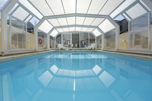 室內游泳池，開放時間為 10:00 至 19:00，提供泳池遮陽傘和日光浴躺椅