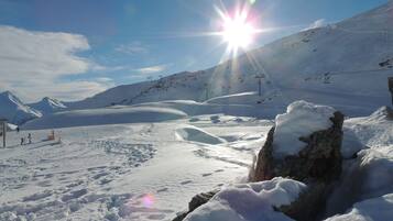 Paesaggio montano innevato con cielo sereno, impianti di risalita e un lago ghiacciato.