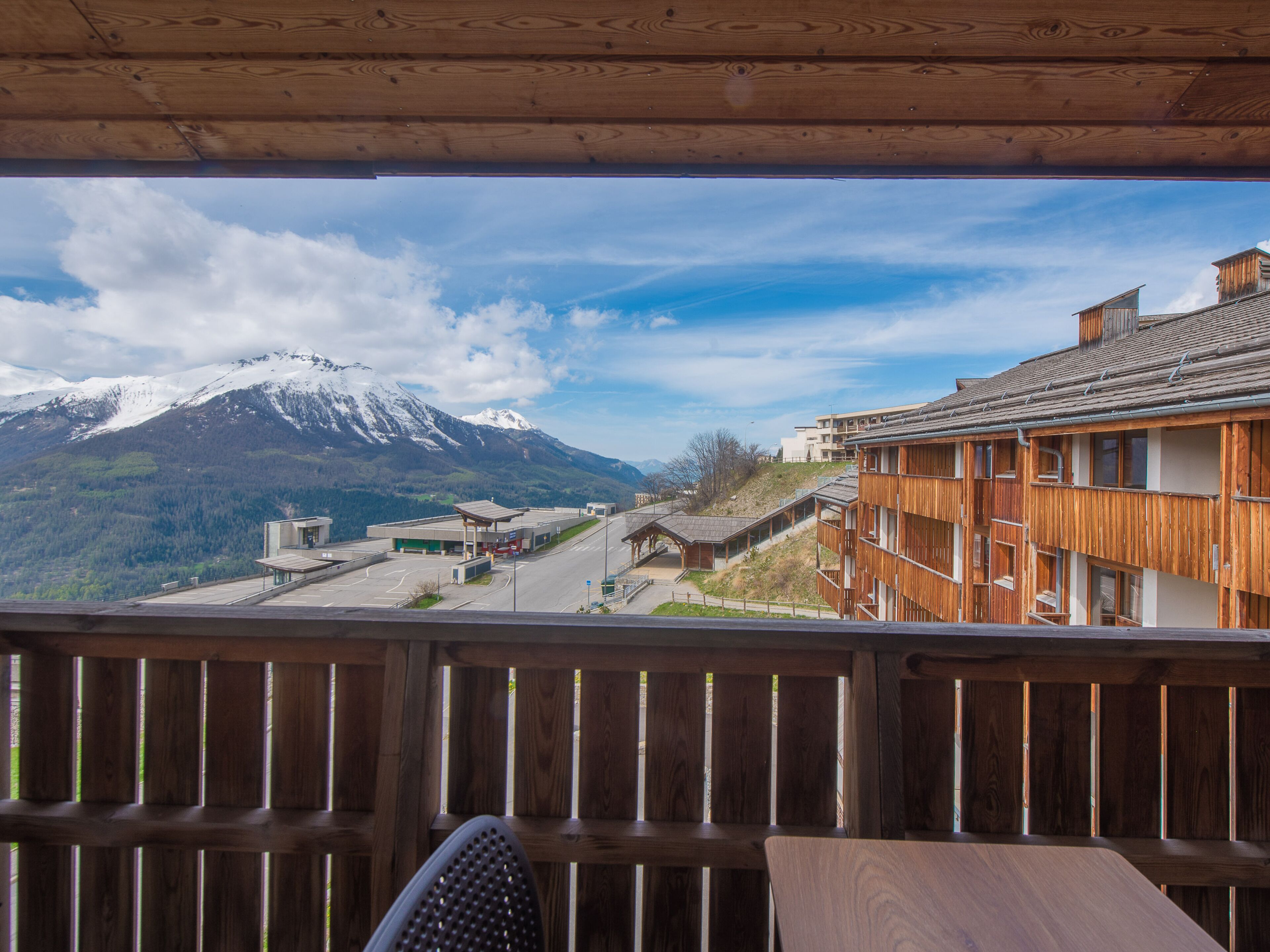 A wooden balcony overlooking a mountain with a ski resort in the background.