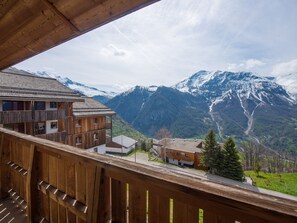 Un edificio de madera con balcones que dan a un valle y montañas nevadas.