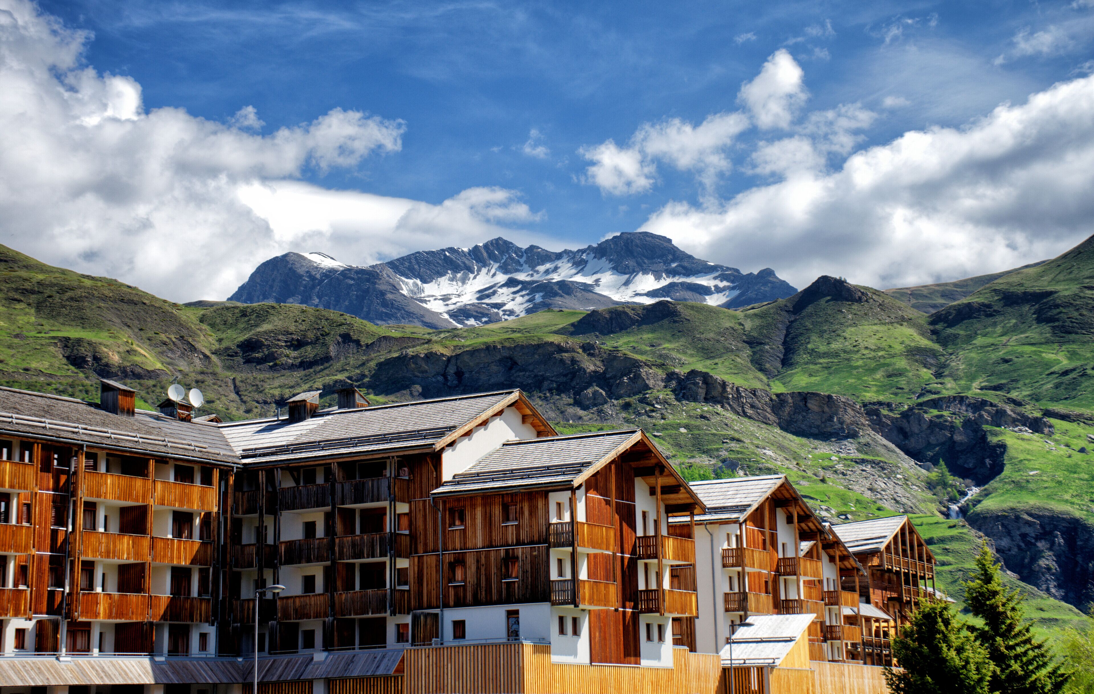 Un chalet de montagne doté de balcons en bois et offrant une vue sur les sommets enneigés.