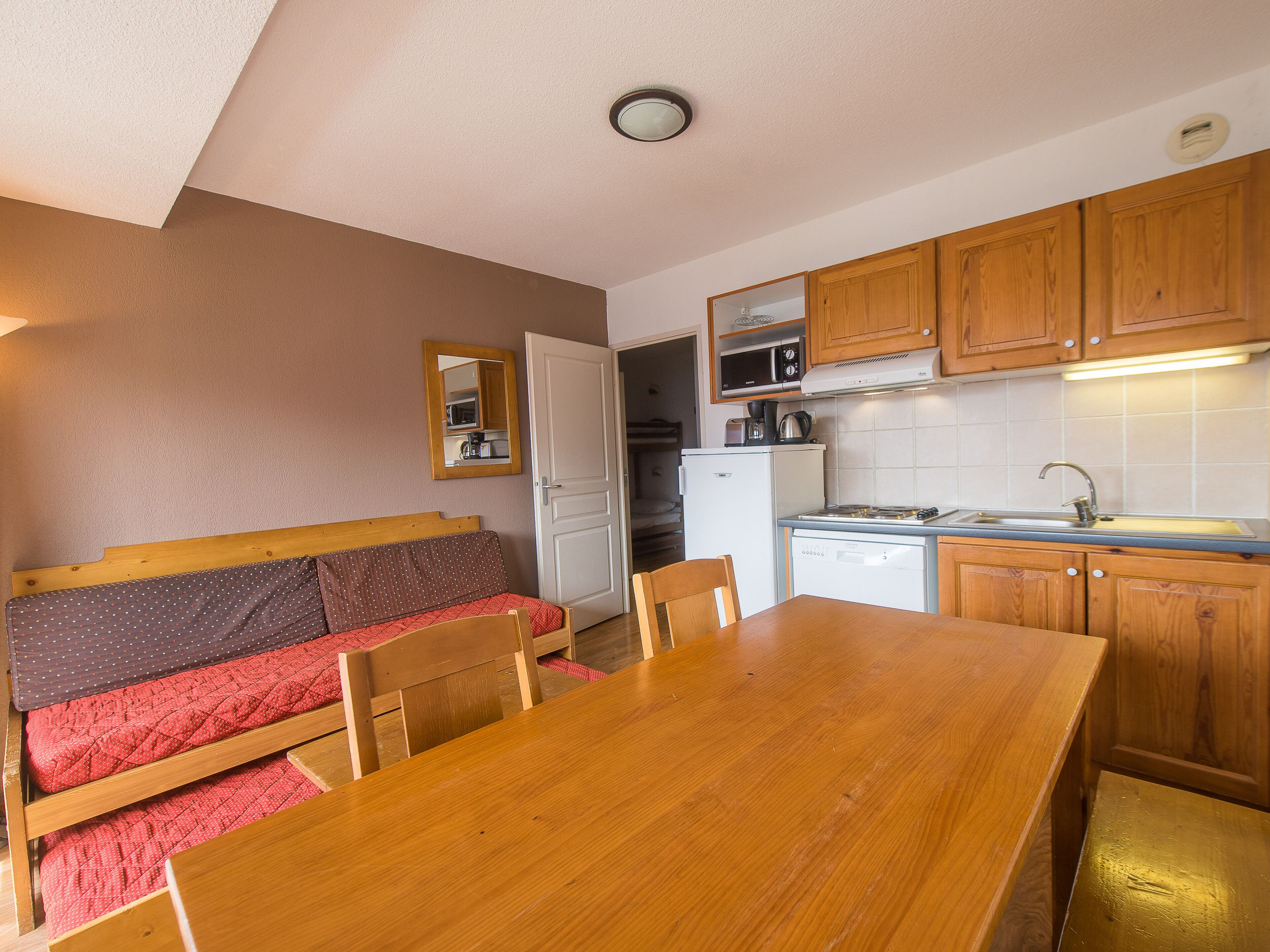 A compact kitchen with wooden cabinets, a microwave, a refrigerator, and a sink.