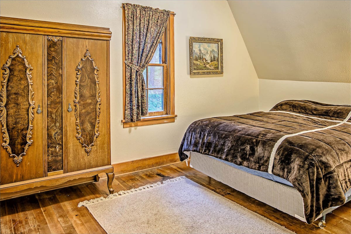 Une chambre à coucher avec un grand lit, une armoire en bois, une fenêtre avec des rideaux et un tableau encadré au mur.