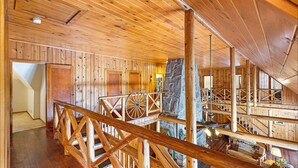 A spacious wooden interior with a high ceiling, wooden railings, and a stone pillar. - Diamond Belle Guest Ranch (Wauconda)