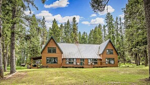 A wooden cabin with a metal roof, surrounded by tall trees and a grassy area. - Diamond Belle Guest Ranch (Wauconda)