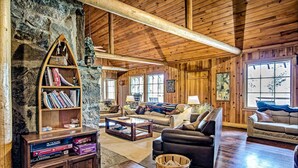 A spacious living room with wooden walls and ceiling, a large bookshelf, two sofas, and a coffee table. - Diamond Belle Guest Ranch (Wauconda)