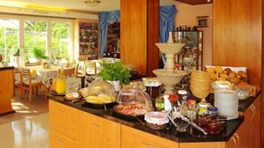 Un buffet della colazione con diversi cibi e una sala da pranzo con sedie e tavoli.