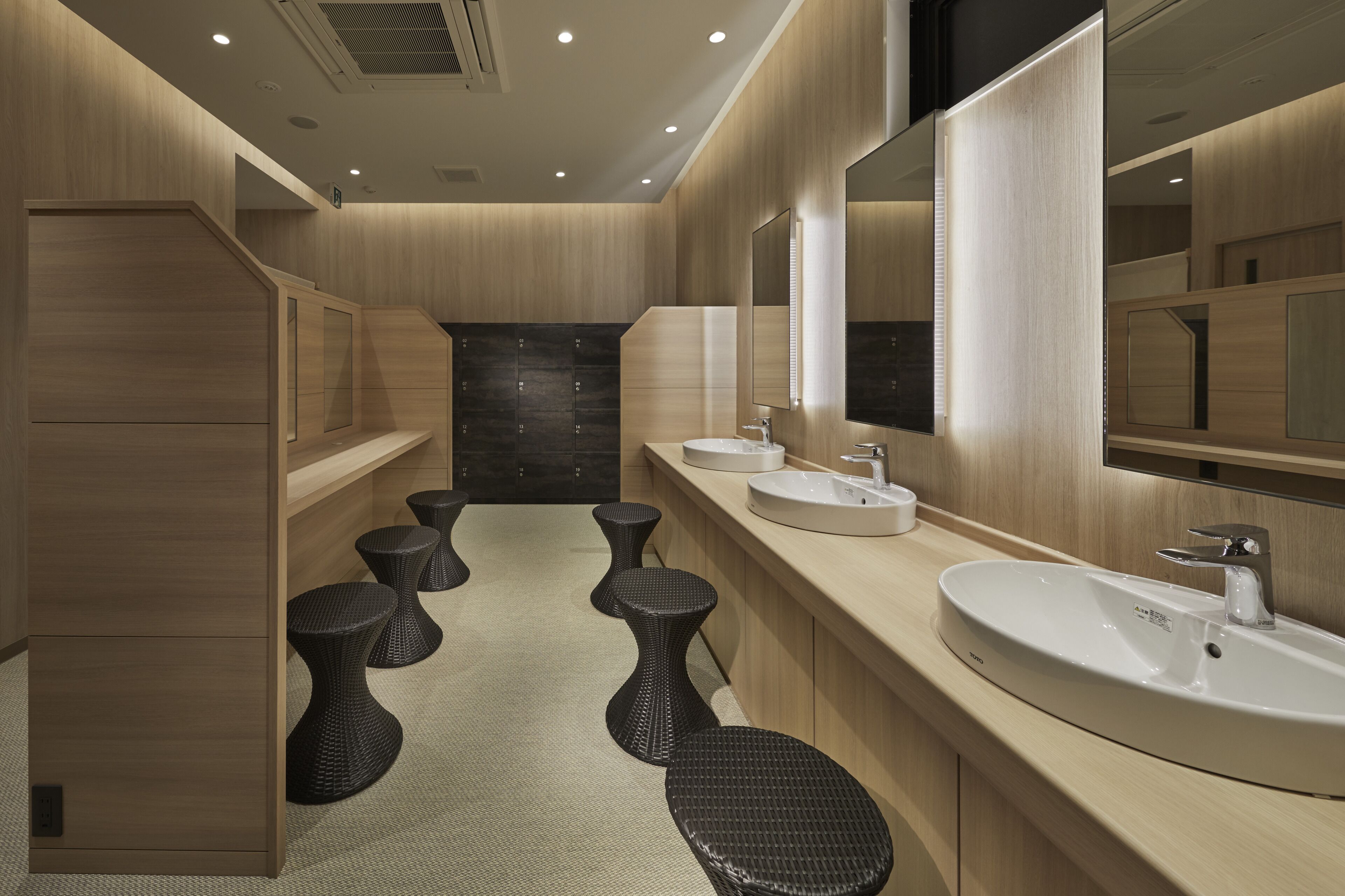 A modern bathroom with wooden walls, a central sink, and a mirror.