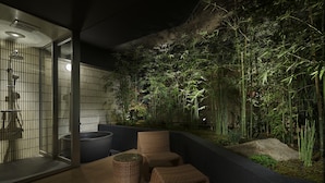 Un área de estar moderna al aire libre con mobiliario de mimbre y un jardín de bambú de fondo.