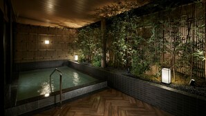 Un área de spa con jacuzzi, pared de bambú y suelo de baldosas.