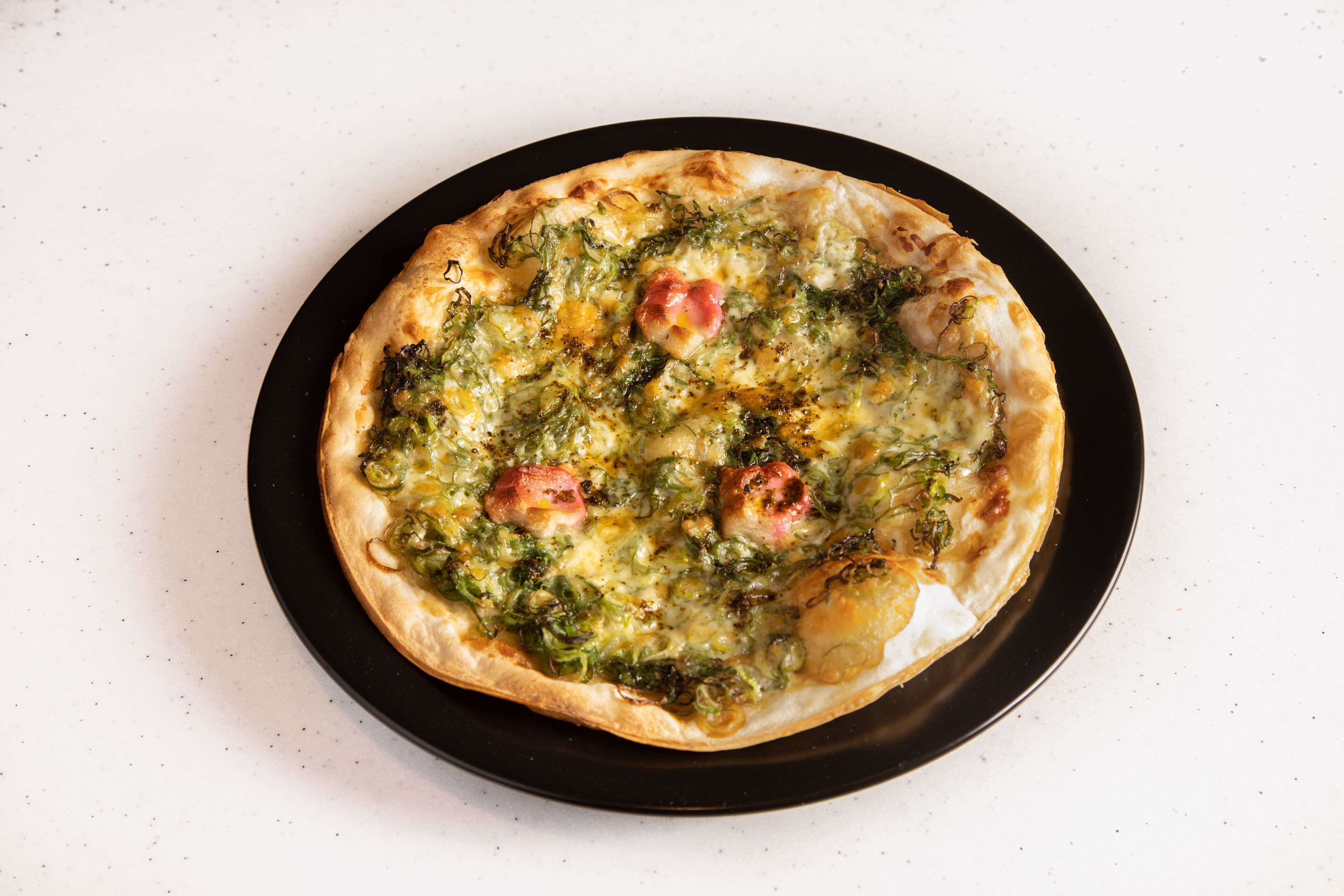 Una pizza sobre un plato negro.