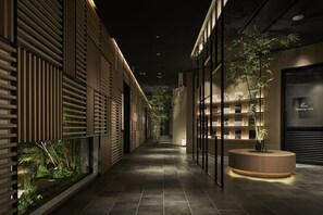 A modern indoor corridor with a reception desk, bamboo plants, and a smoking area. - Royal Twin Hotel Kyoto Hachijoguchi (Kyoto)