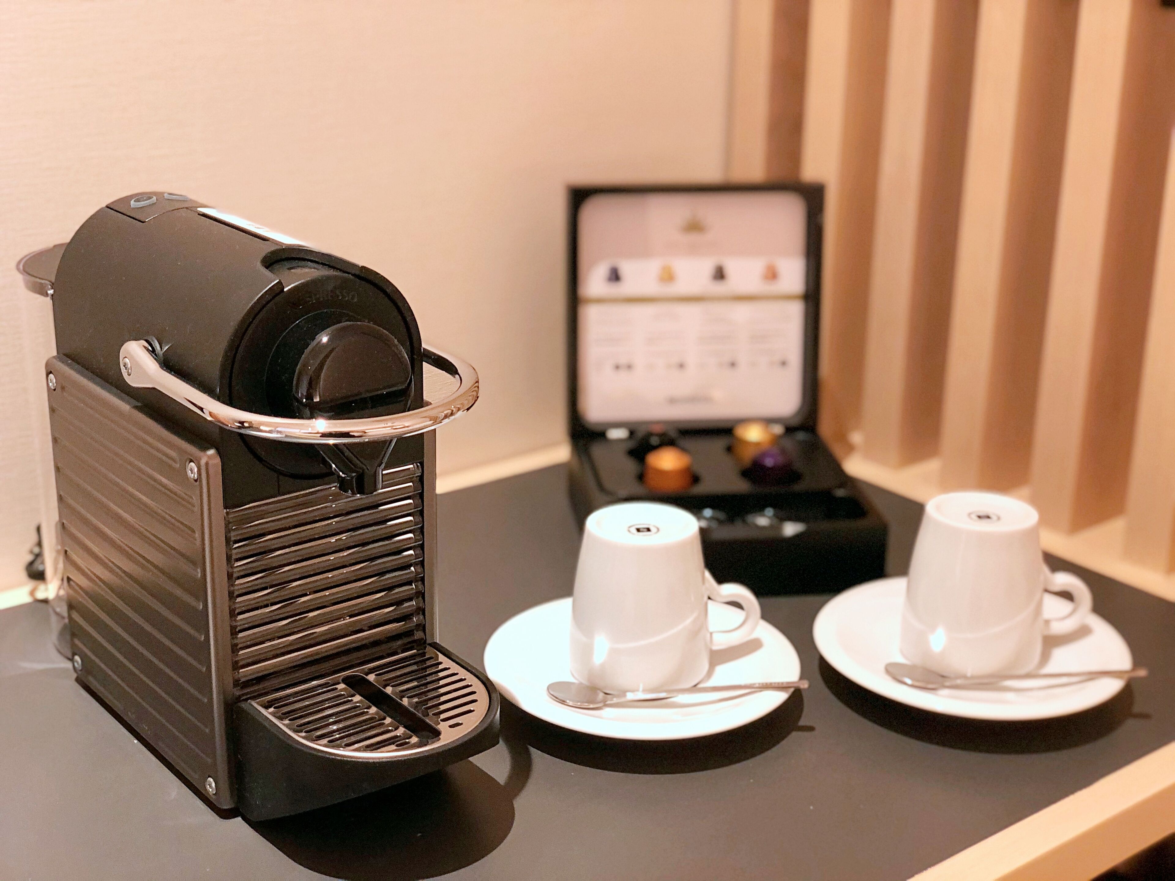 A coffee machine with two cups and a menu stand on a table.