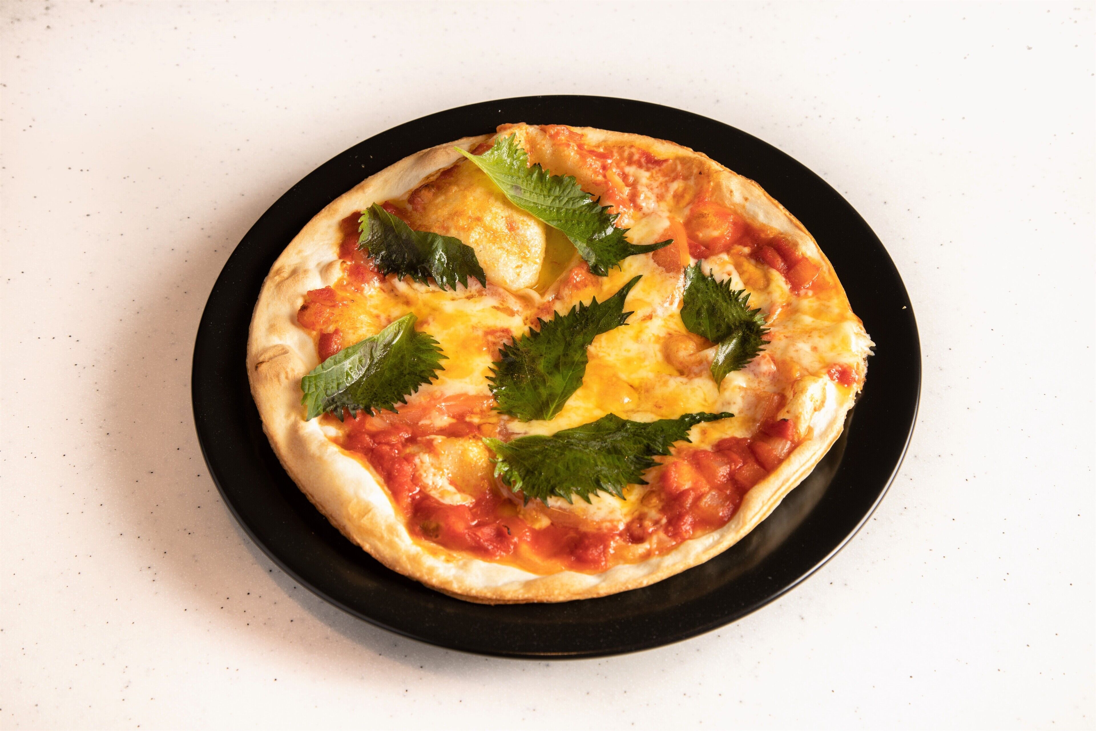 Eine Pizza auf einem schwarzen Teller.