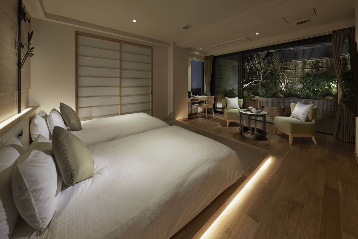 A spacious bedroom with a large bed, a desk, and a seating area with chairs.