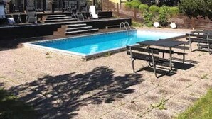 A swimming pool with lounge chairs and a covered pavilion. - Yxnerum Hotell (Atvidaberg)