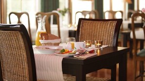 A breakfast setting with wicker chairs, a table set with plates, a glass pitcher, and a candle. - Yxnerum Hotell (Atvidaberg)