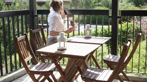 A wooden table and chairs on a balcony with metal railings, a white lantern, and a person sitting. - Yxnerum Hotell (Atvidaberg)
