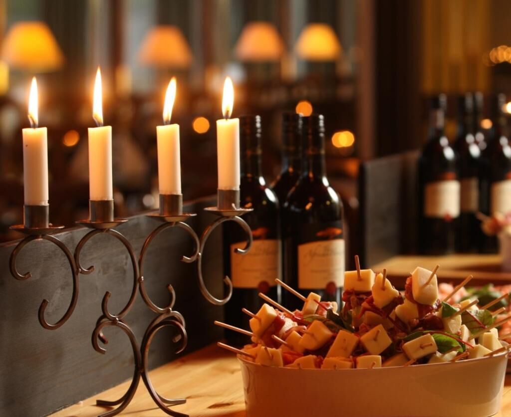 A table with candles, bottles, and cheese skewers.