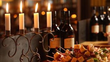 A table with candles, bottles, and cheese skewers.