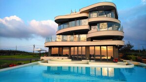 A modern multi-story building with a pool in front. - Laguna Villas & Resorts (Magong)