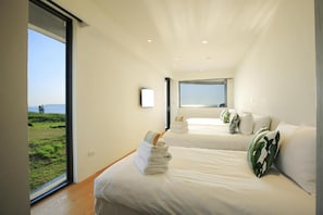 A modern hotel room with two beds, a large window offering a view of the outdoors, and a small television on the wall. - Laguna Villas & Resorts (Magong)