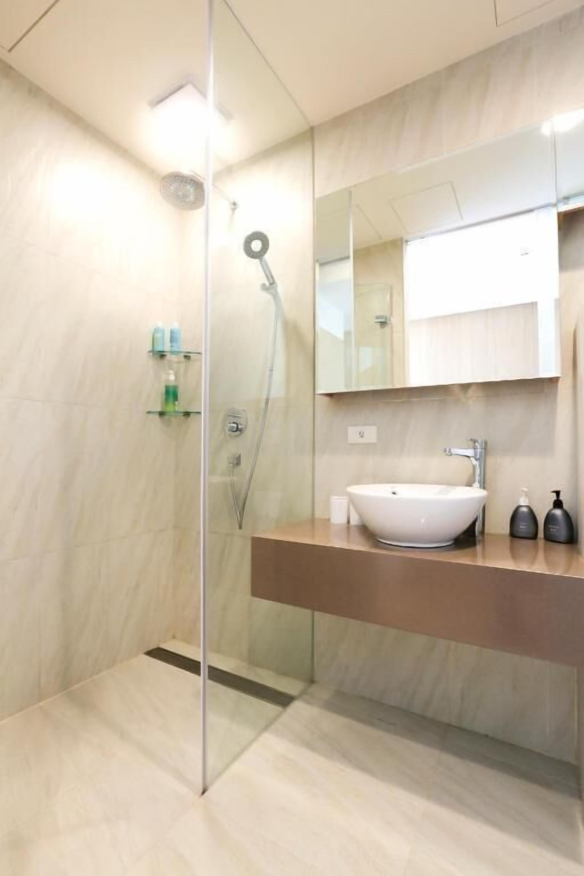 A modern bathroom with a glass-enclosed shower, a white sink, and a large mirror above the vanity.