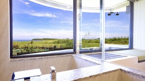 A bathroom with a large window, a marble countertop, and a view of a green landscape. - Laguna Villas & Resorts (Magong)