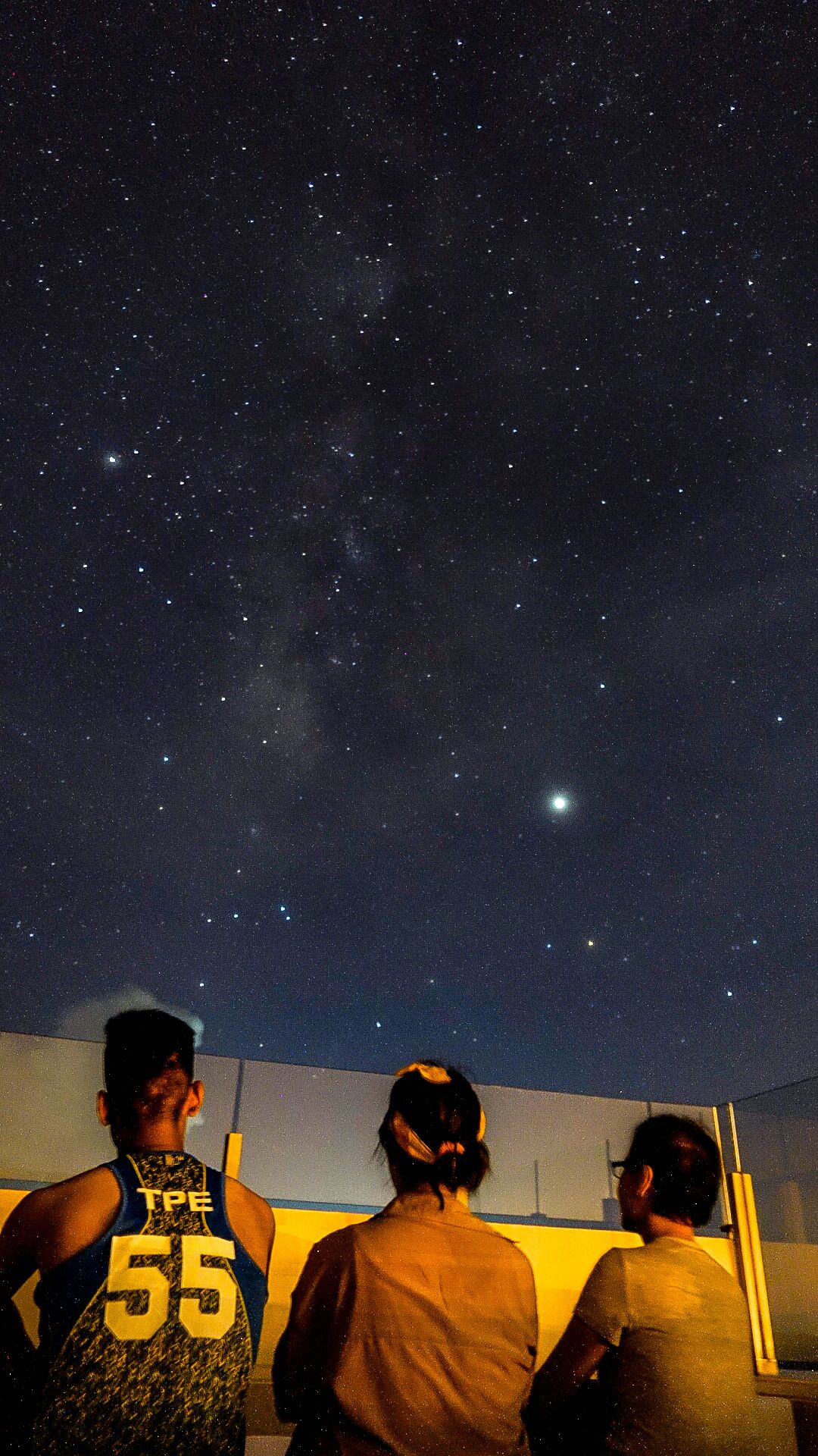 Tres personas contemplando un cielo estrellado.