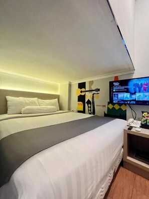 Habitación de hotel con cama, televisión y una guitarra en la pared.