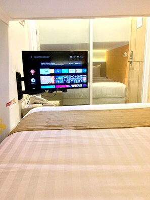Habitación de hotel con una cama, un televisor montado en la pared mostrando una pantalla de actualización del sistema y un armario de madera.