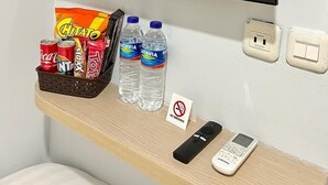A TV screen displaying the Netflix logo, a snack basket with chips and drinks, and a no-smoking sign. - Front One Cabin Sunter (Jakarta)