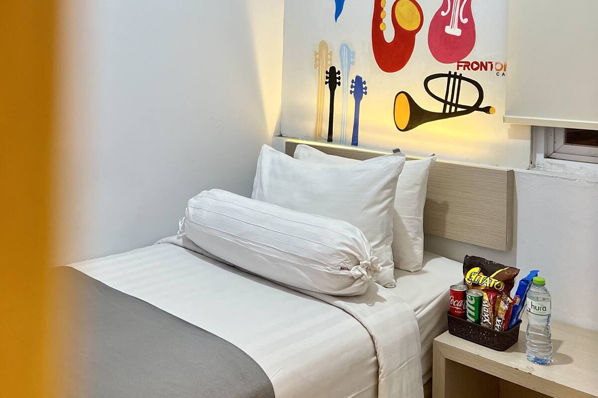 A hotel room with a bed, a nightstand, and a wall decorated with musical instruments and the word "JAZZ".