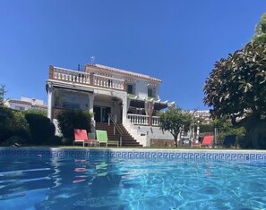 Een buitenzwembad, parasols bij het zwembad en ligstoelen