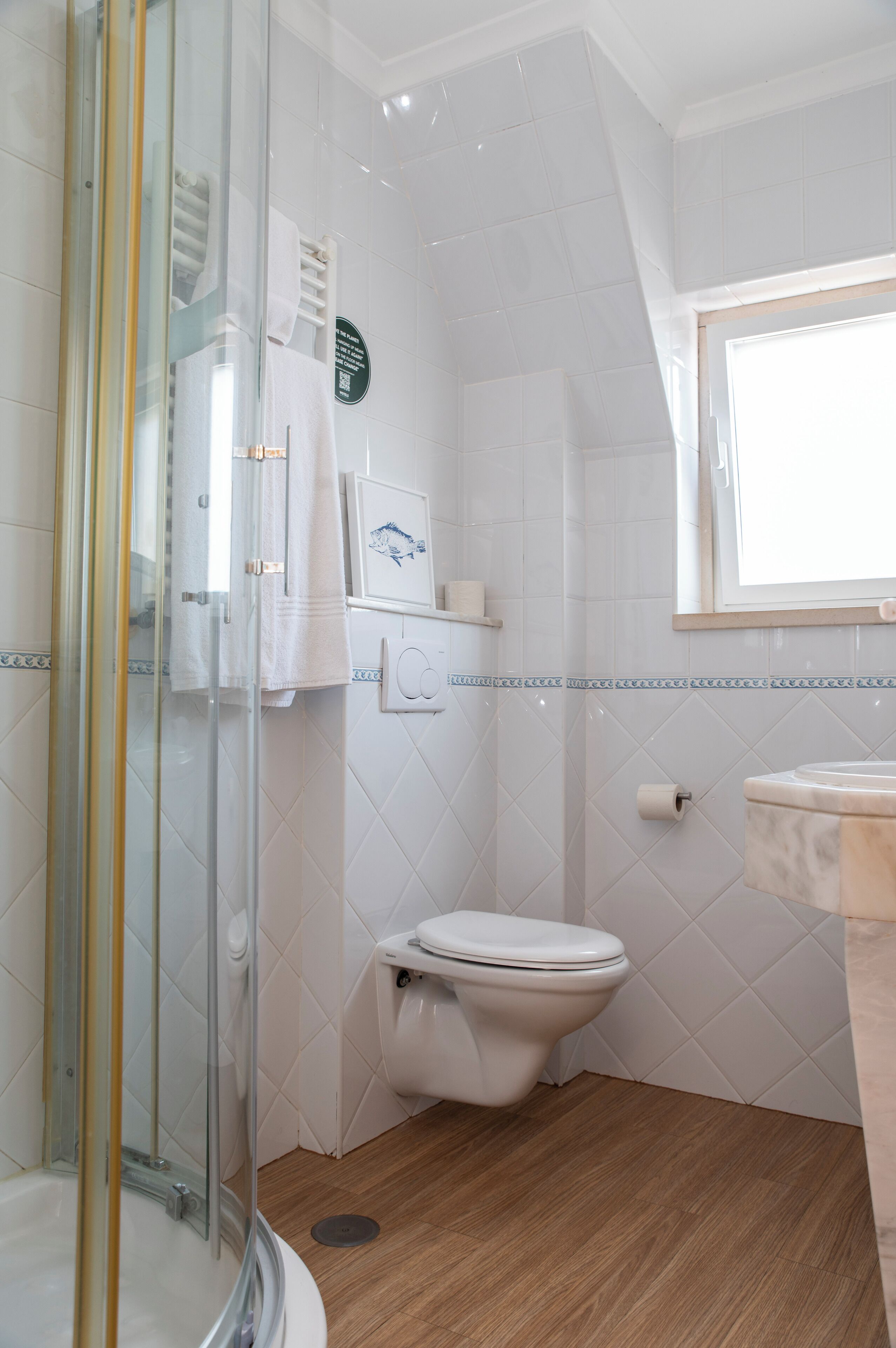 Baño con cabina de ducha de vidrio, inodoro y lavamanos.