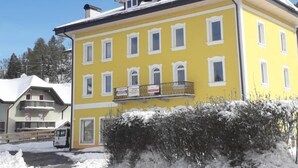 Un edificio amarillo con varias ventanas y un balcón, rodeado de nieve.
