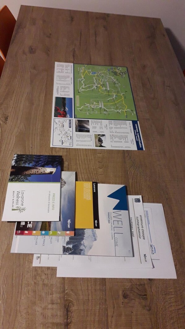 A table with various travel brochures and maps, including one for Lavarese and another for a destination in Italy. - Rosticaffè (Lavarone)